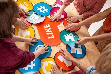 Group of people arranging colorful circular icons with social media symbols and the word LIKE on a table.